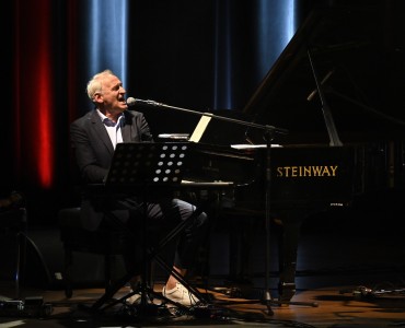 Krzesimir Dębski grający na instrumencie klawiszowym i śpiewający do mikrofonu.. Kliknij, aby powiększyć zdjęcie.